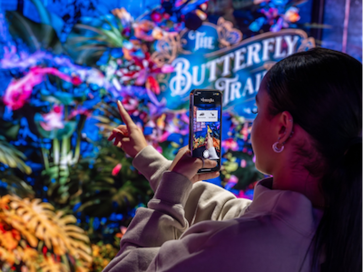 Women interacts with The Butterfly Experience at Outernet using her smartphone