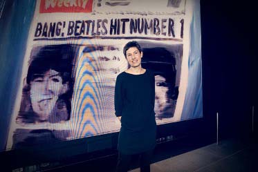 Em Cooper standing in front of Beatles artwork