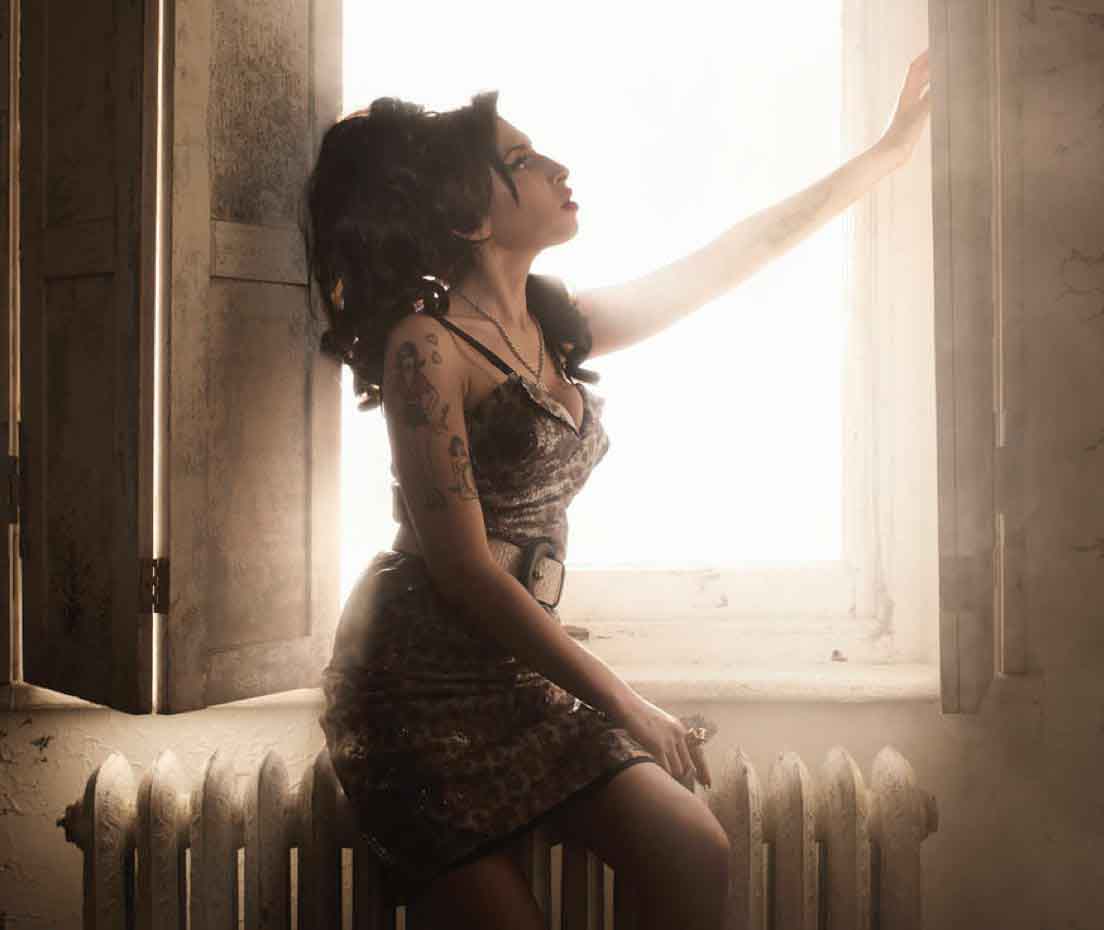 Amy Winehouse sitting on a radiator by a window