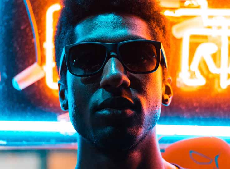 Man wearing shades in front of a neon sign